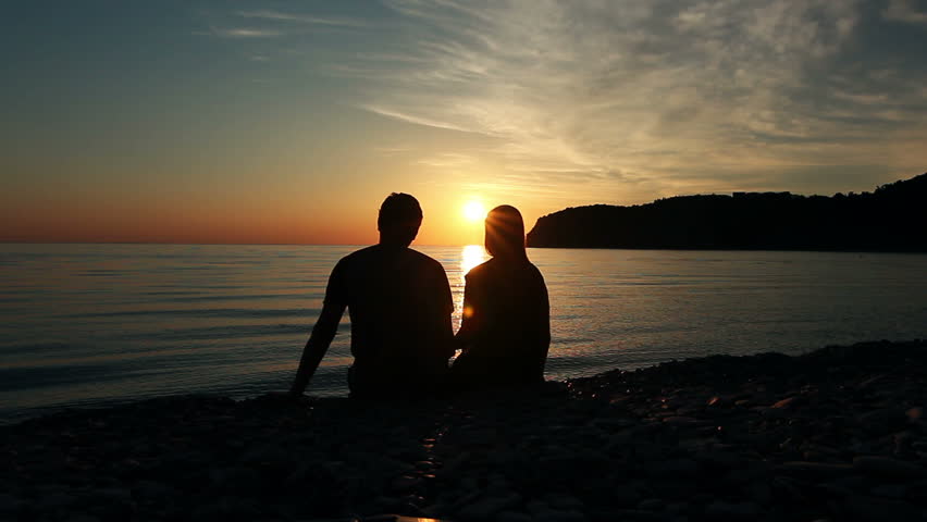 Couple on the shore of the sea, Romantic Couple at Sunset. Two people in love at