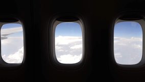 Three illuminators in flying airplane with view to clouds and part of wings, mobile phone video.