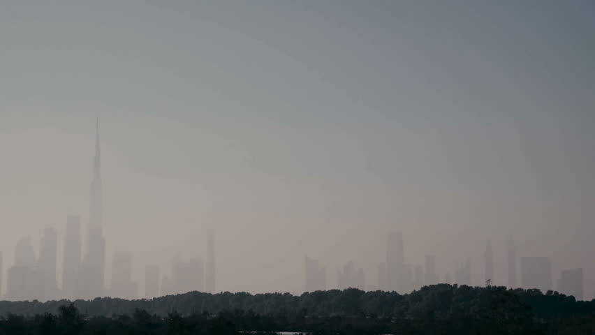 Silhouette of skyscrapers and Burj Khalifa in Dubai through the haze and smog from the heat. East of the country. Modern Famous City Dubai Skyline Dusk Orange Sky Light After Sunset Burj Khalifa