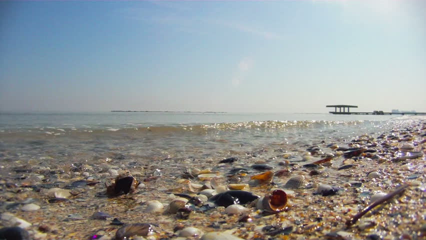 Sand and shells with breaking waves, underwater camera