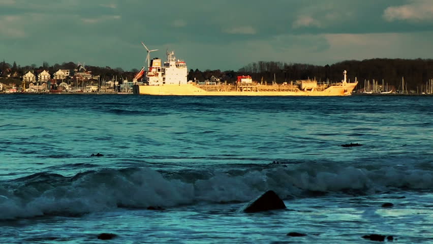 Rolling waves and cargo ship on coastline of Laboe, Kiel, Germany, panning