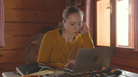 young female working on laptop at home, cozy log cabin interior, 