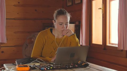 young female working on laptop at home, cozy log cabin interior, 