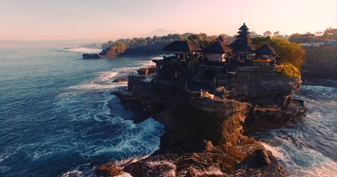 Pura Tanah Lot temple on a rocky island. A cultural symbol of Indonesia. Classic oriental temple and ocean. Sunlight. Aerial view. Bali, Indonesia