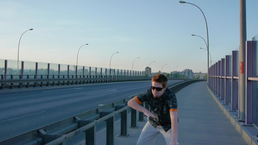 Red haired guy dances next to street with car traffic