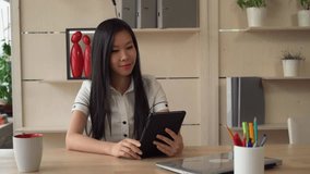 Asian business lady using touch screen tablet talking with friend or client use application. wearing in casual formal white shirt
