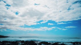 Timelapse shot of waves breaking on rocky shore. Idyllic aerial shot of clouds rolling over ocean. Scenic view seascape against sky. 4K resolution.