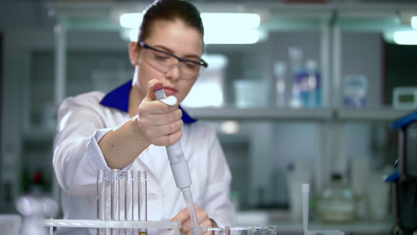 Researcher working with dropper in laboratory. Lab worker using laboratory equipment. Female researcher using pipette in lab. Laboratory woman filling test tubes with chemical liquid