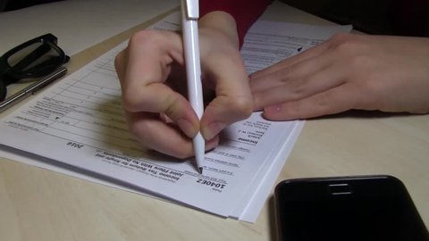 A Woman Is Writing First And Last Names In The US Individual Income Tax Return Form 1040, Year 2016