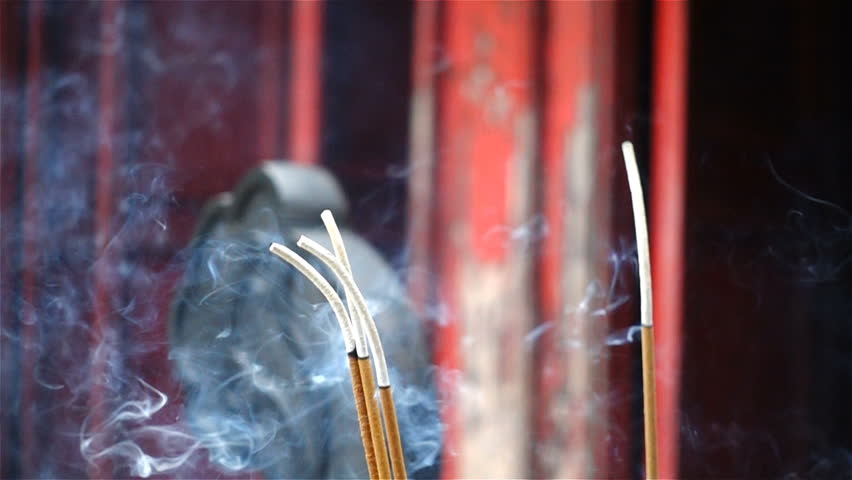 Close up slow motion of burning Incense stick in brazier at the Ngoc Son Temple (Temple of the Jade Mountain) in Hanoi, Vietnam. Sending prayers directly up to divine Spirit during Chinese New Year.