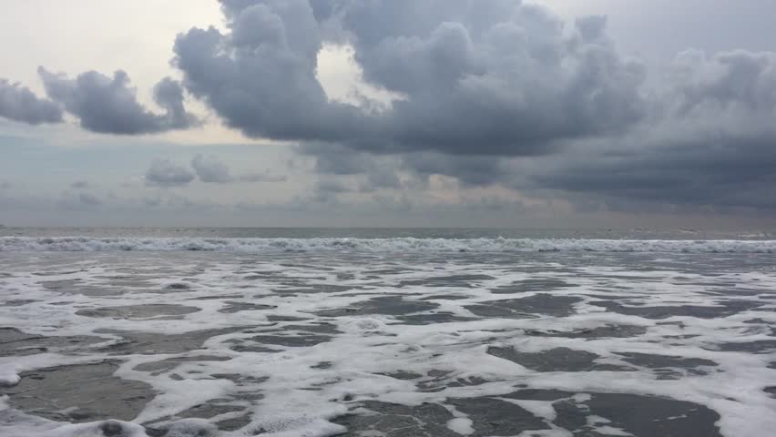 Surf from blue ocean waves lapping over empty sandy beach