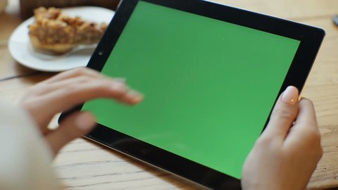 Businesswoman using tablet computer with green touch screen in cafe