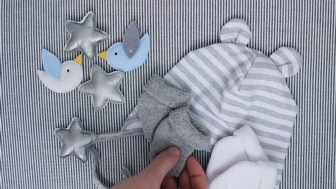 mother puts baby socks on the bed with baby clothes