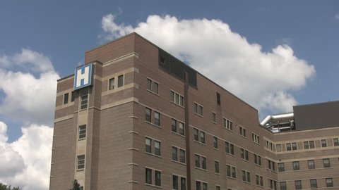 A hospital with blue sky and timelapse clouds in the background.
