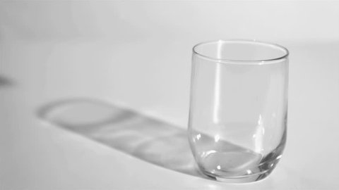 Two ice cubes in a super slow motion rebounding in a glass against a grey background