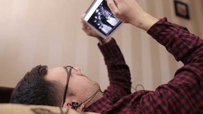 Caucasian man using digital tablet on sofa and listening to music