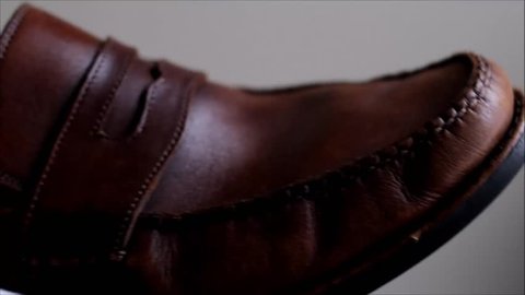 Man cleaning brown leather shoe with white cloth
