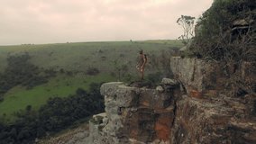 4k Drone footage of young free climber and hiker, climbing mountain cliff and drinking water from water bottle at sunset, South Africa. 
