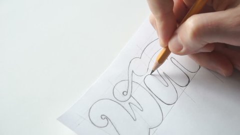 Lettering or logo creating with a pencil on white paper. Handlettering design creation process. Designer drawing letters with pen. Sketch artwork with liner marker. Calligraphy work.