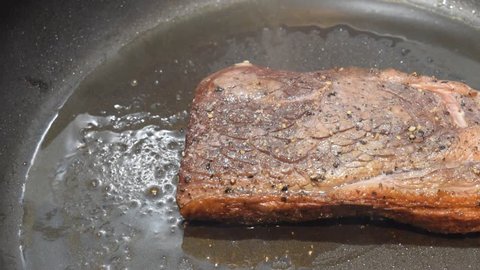 Left to right camera pan on a hot crispy rump steak in an iron nonstick pan