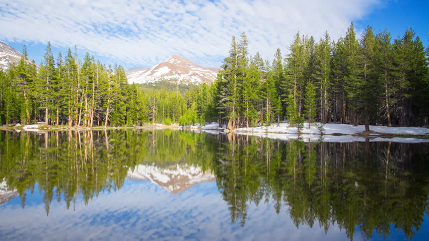 Time lapse with pan left motion of perfect reflection at calm alpine lake in Yosemite National Park, California