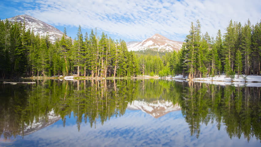 Time lapse with pan right motion of perfect reflection at calm alpine lake in Yosemite National Park, California
