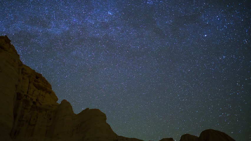 Astrophotography timelapse with pan left motion of star trails over sandstone canyon walls at Red Rock Canyon State Park in Mojave Desert, California