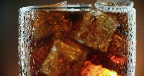 Cola with ice. Extreme close up of Cola with Ice cubes and bubbles in the big rotating glass. Soda.4k stock video footage.