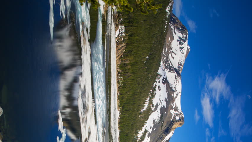 Time lapse with pan motion of melting ice in reflective alpine lake in Yosemite National Park, California -Vertical Shot-