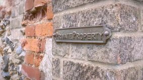 A clip of a wrought iron private property sign on a brick wall 