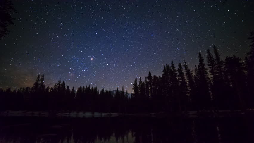 Astrophotography time lapse with tilt down motion of milky way galaxy rising over alpine lake reflection in Yosemite National Park, California