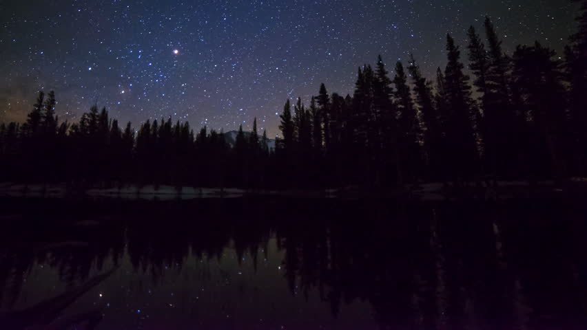 Astrophotography time lapse with pan left motion of milky way galaxy rising over alpine lake reflection in Yosemite National Park, California