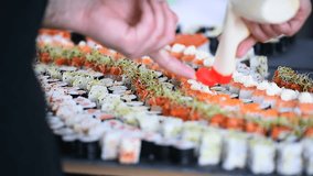 Hands arranging different sushi appetizers on a plate
