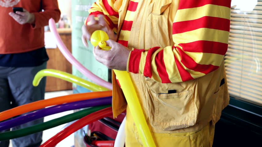 Clown makes balloon animals for small children.