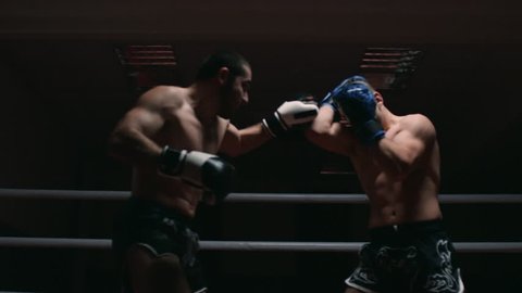 Two muscular mixed martial arts athletes fighting in the ring in slow motion