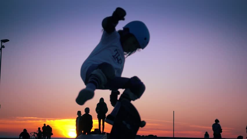 Silhouette of skater on skateboard jumping over sunset sky at Venice Beach skate park, California. Slow motion