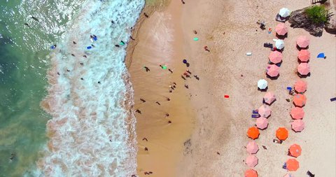 Umbrellas, deck chairs and tourists relaxing on the beach. Dreamland famous balinese beach. Aerial top view. Bali, Indonesia