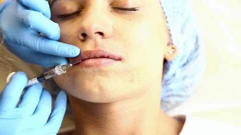 Young woman on lip Augmentation in a clinic. Anesthetic injection Silicone implant lips thickening injection