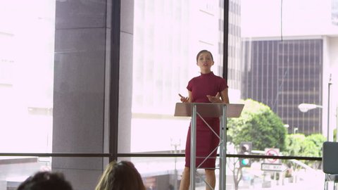 Young woman at a lectern presenting a business seminar, shot on R3D
