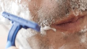 Close-up of male hand shaves facial hair slow-mo 1080p FullHD footage - Slow motion of man with disposable razor shaving beard on cheek 1920X1080 HD video