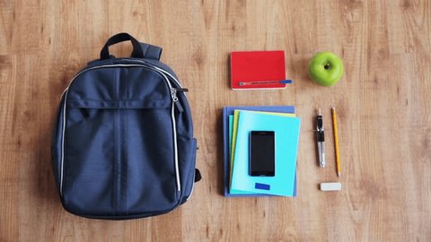 people, school supplies, education and personal stuff concept - hands packing schoolbag