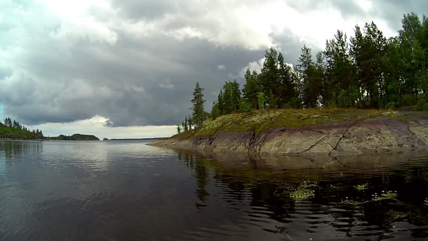 Quiet weather on Lake Ladoga near the stone islands covered with moss. Dark clouds on the sky. Canoeing on the lake.