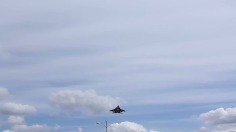 F15 fighter jet flying overhead on cloudy day.