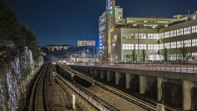 Time Lapse of subway railway tracks at night. Subway trains passing by, office building in the background