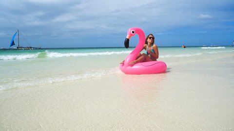 sexy girl floats on an inflatable mattress on the beautiful white beach with clear water
