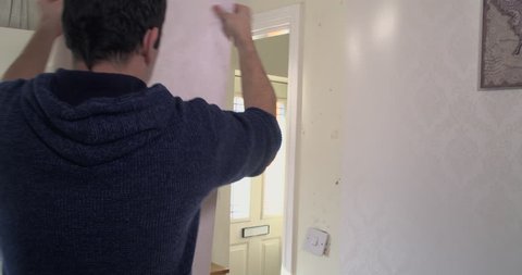 Adult male putting up some new wallpaper in his family home