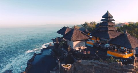 Pura Tanah Lot temple on a rocky island. A cultural symbol of Indonesia. Classic oriental temple and ocean. Aerial view. Bali, Indonesia