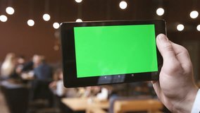 A man holds a blank tablet PC with a green screen for your own custom content.