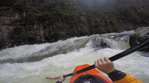 A first person video of a kayaker rolling and flying down a dangerous rapid