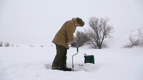Fisherman, bore hole on the snow-covered lake in search of a good fishing place